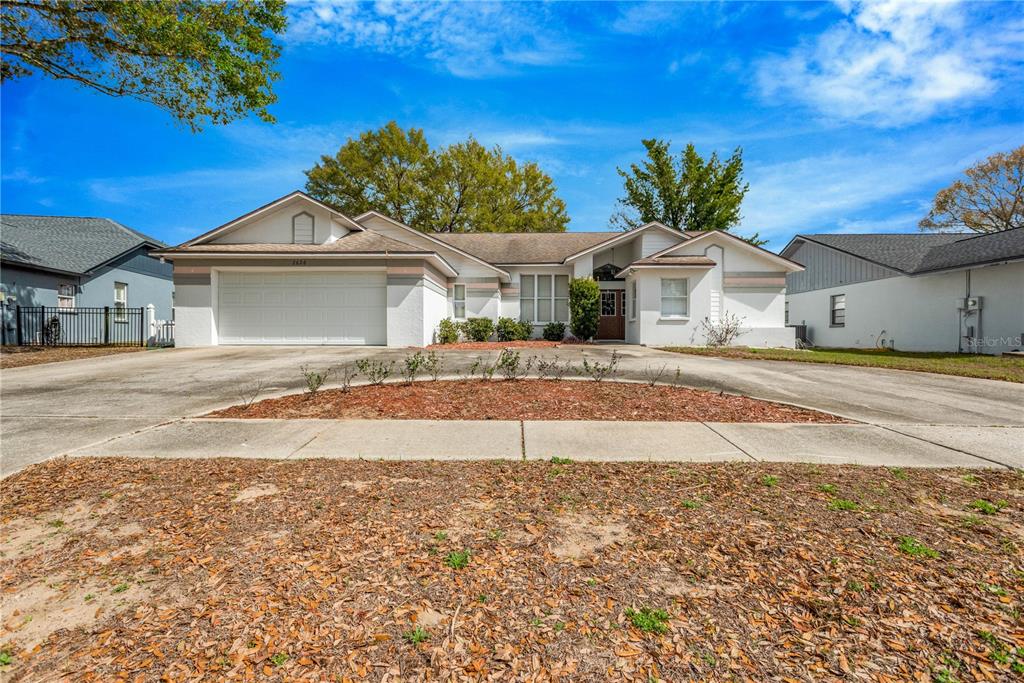 A single-story house with a white stucco exterior, a two-car garage, and a concrete driveway — 2626 CRESTFIELD DRIVE, VALRICO, FL
