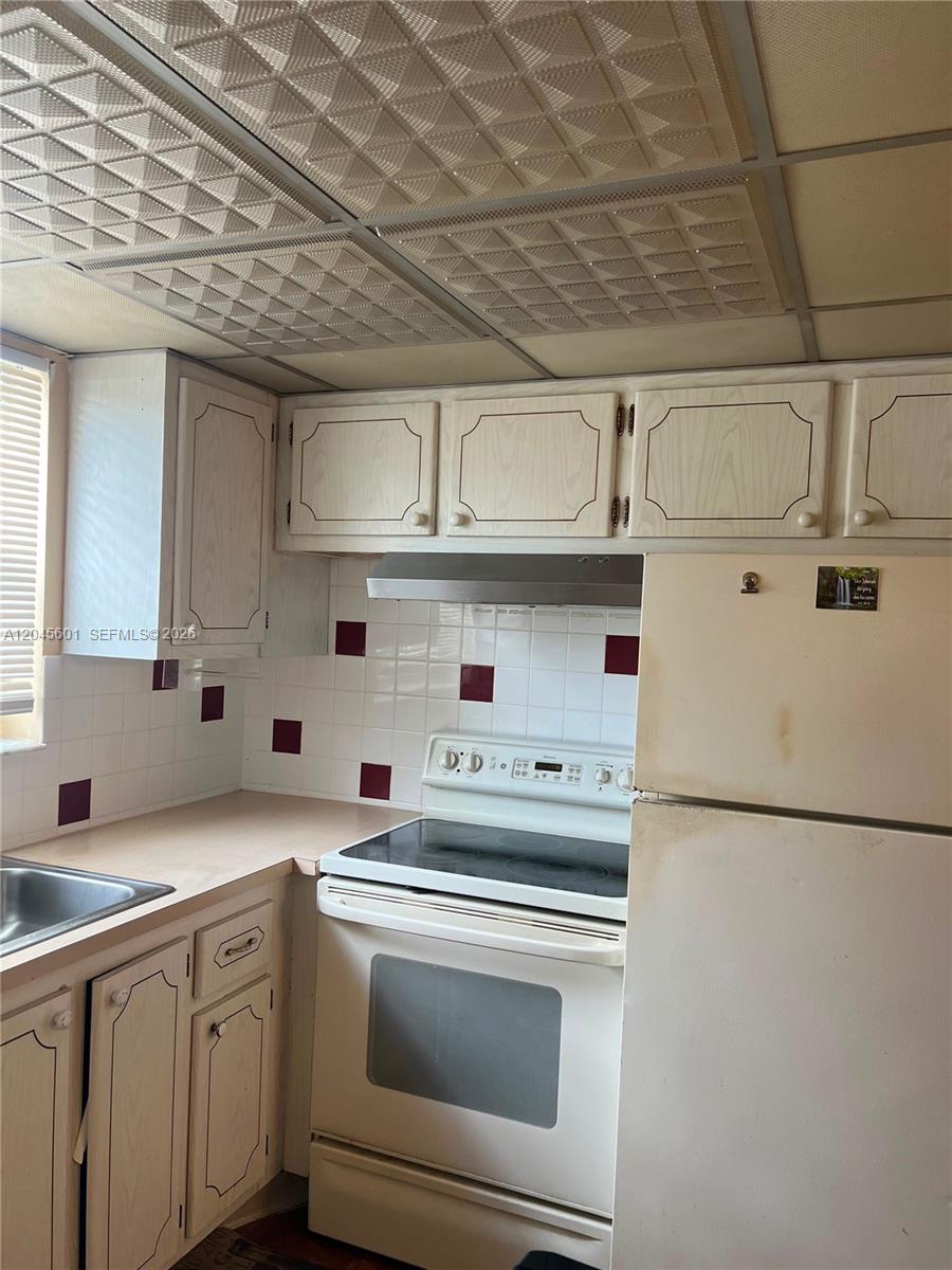 A kitchen features white cabinets, a white stove, a refrigerator, and a drop ceiling — 391 Windsor Q # 0, West Palm Beach FL 33417, WEST PALM BEACH, FL