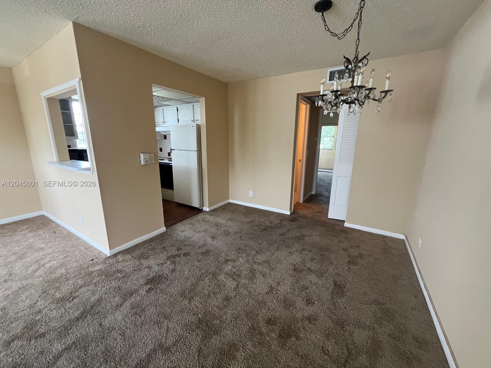 A carpeted dining area features a chandelier and an opening into a kitchen — 391 Windsor Q # 0, West Palm Beach FL 33417, WEST PALM BEACH, FL