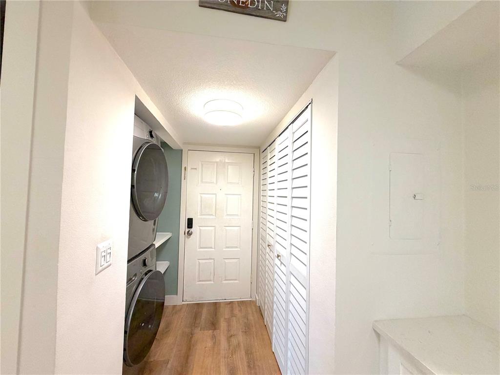 A laundry area features stacked appliances, white louvered closet doors, and a light-colored entry door — 2067 HUNTERS GLEN DRIVE UNIT 312, DUNEDIN, FL