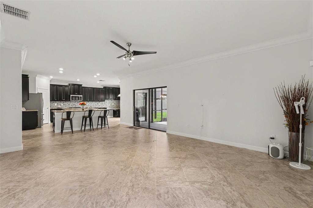 An empty living room with tile floors, a ceiling fan, and sliding glass doors to a patio — 12005 CINNAMON FERN DRIVE, RIVERVIEW, FL