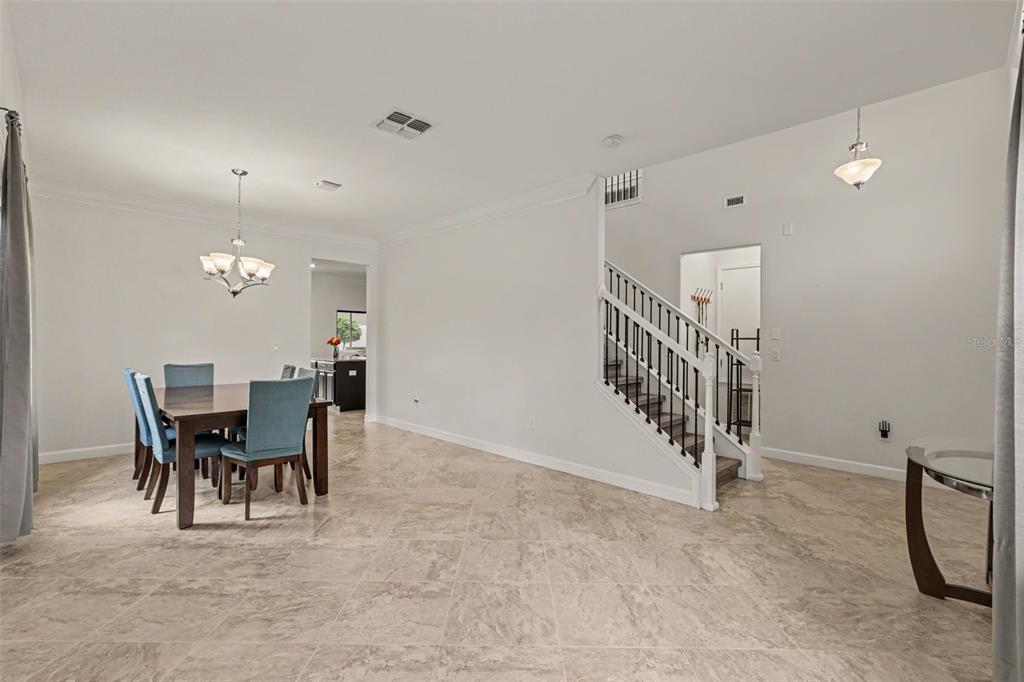 A living room with tile floors, a gray sofa, two armchairs, and a sliding glass door — 12005 CINNAMON FERN DRIVE, RIVERVIEW, FL