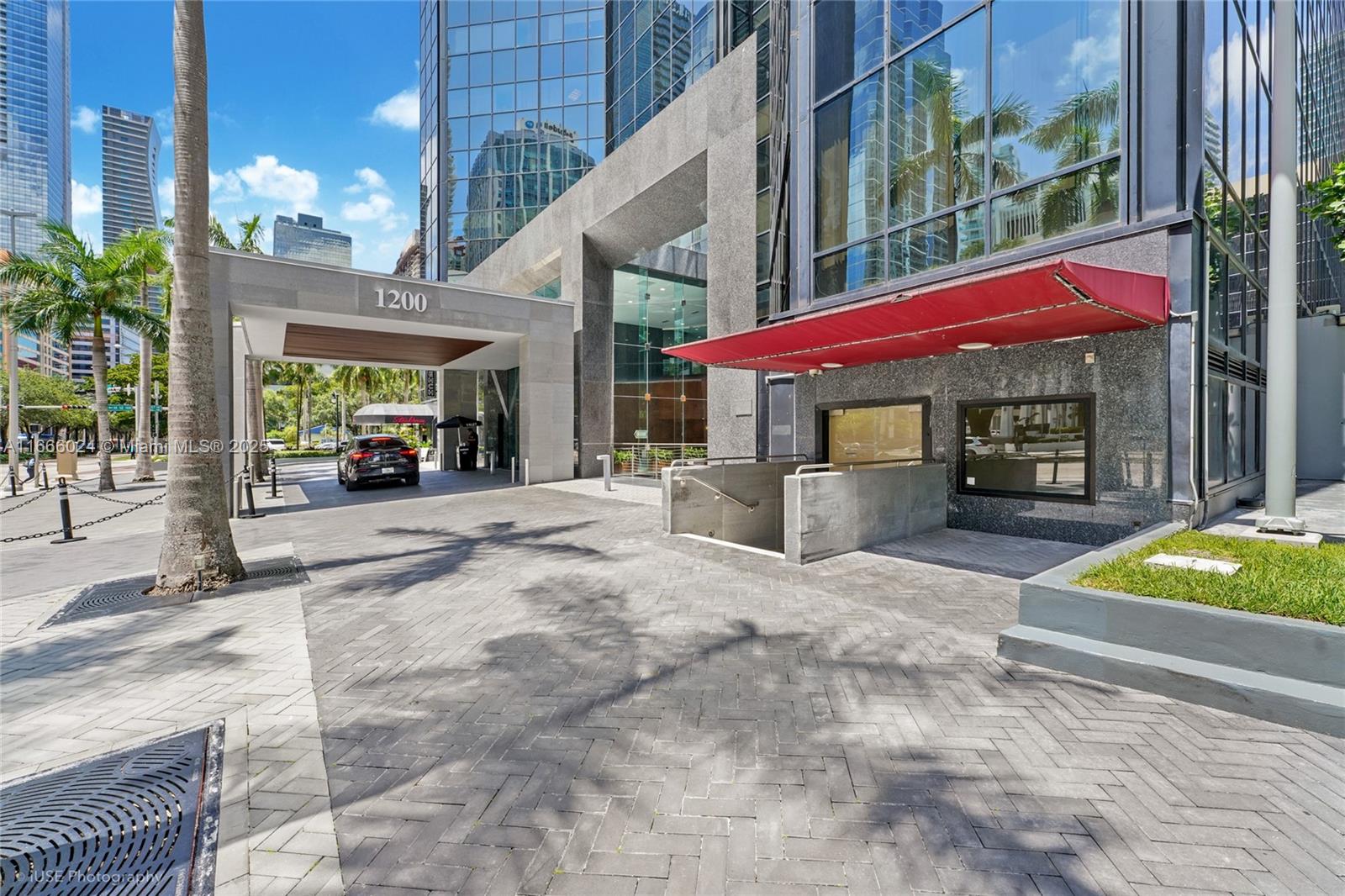 The exterior of a modern office building features a covered entrance, driveway, and red awning — 1200 Brickell Ave # D, Miami FL 33131, MIAMI, FL