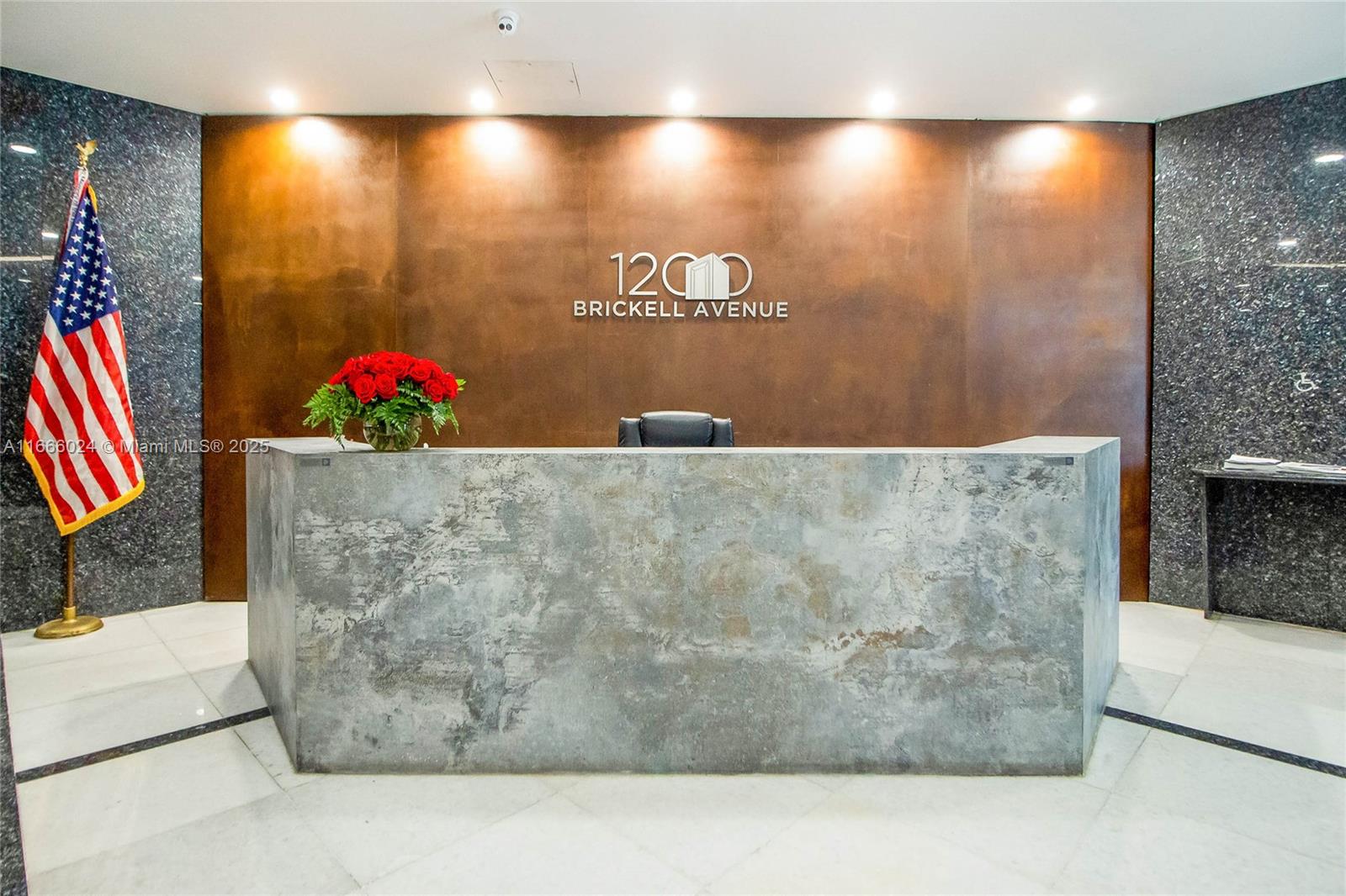 A reception desk with a textured gray front sits in front of a bronze-colored wall — 1200 Brickell Ave # D, Miami FL 33131, MIAMI, FL