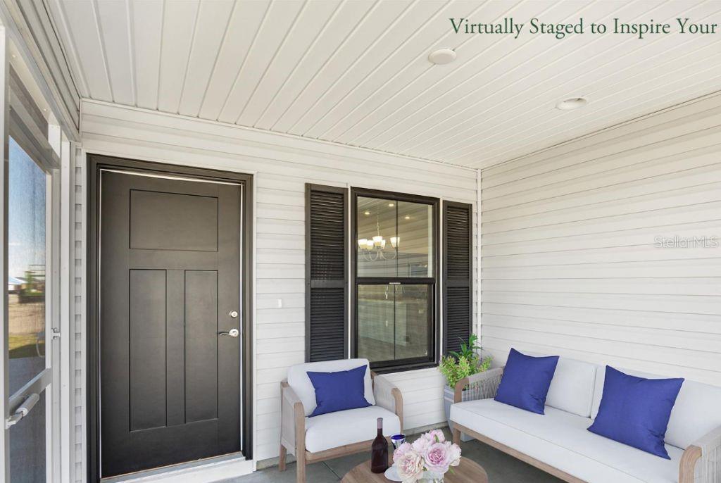 A covered front porch features white siding, a black door, and virtual furniture staging — 1746 BRODY COURT, THE VILLAGES, FL
