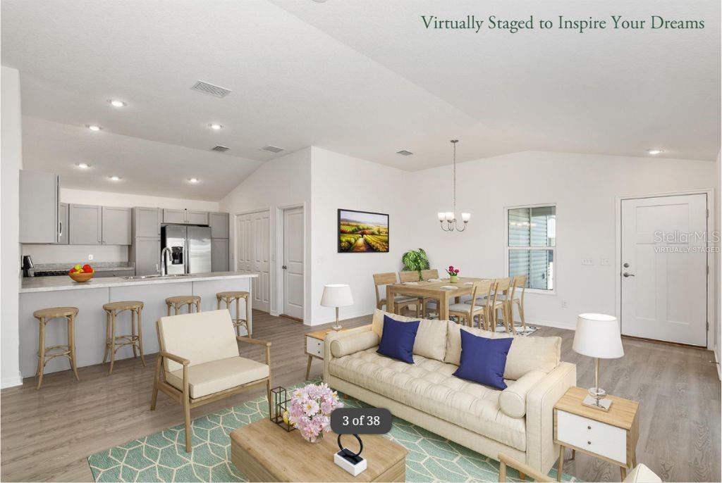 This open-concept living area features a kitchen with light gray cabinets and wood-look flooring — 1746 BRODY COURT, THE VILLAGES, FL