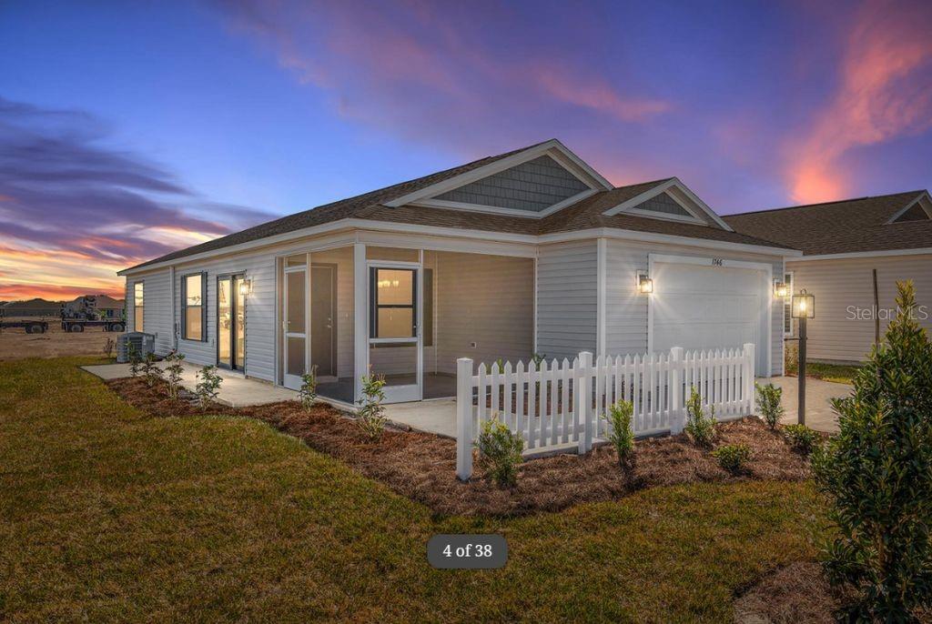 A single-story house with light siding, a screened-in porch, and a white picket fence — 1746 BRODY COURT, THE VILLAGES, FL