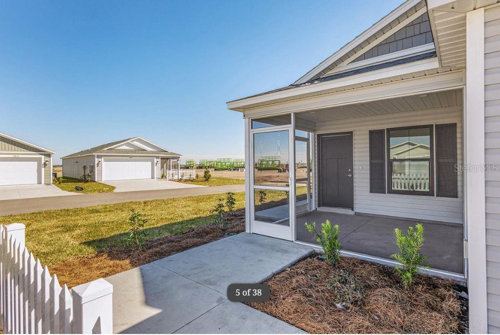 A view of a house exterior featuring a screened-in front porch and a concrete walkway — 1746 BRODY COURT, THE VILLAGES, FL