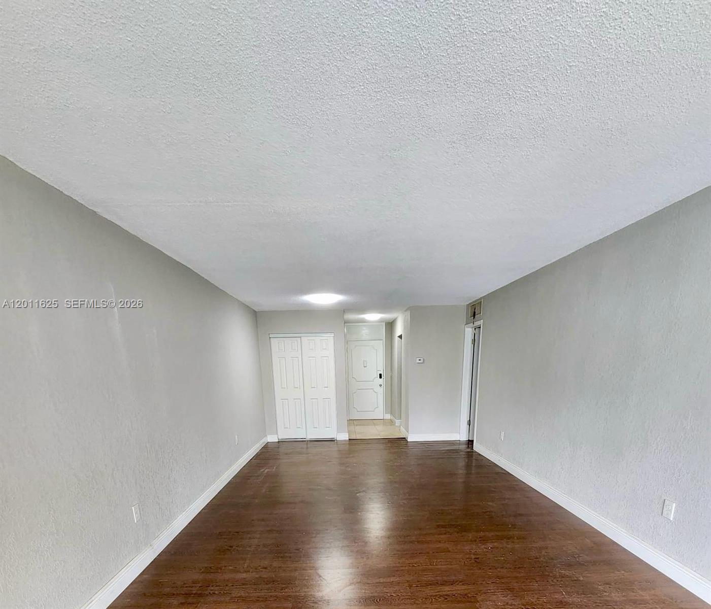 An empty room features gray walls, dark wood flooring, and a white ceiling — 12590 NE 16th Ave # 209, North Miami FL 33161, NORTH MIAMI, FL