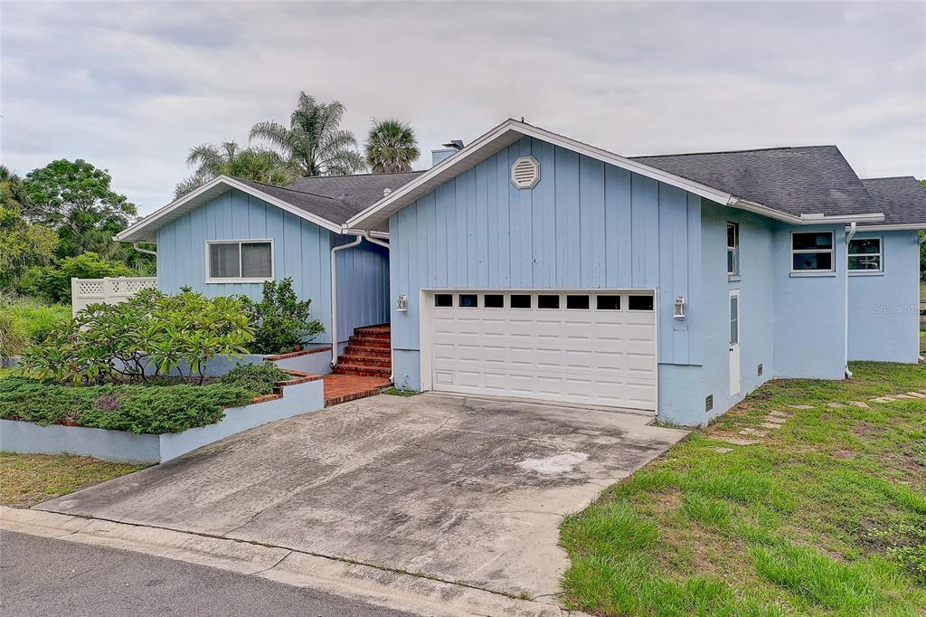 A light blue, single-story house with a brick entryway, a two-car garage, and landscaping — 3214 N SECLUSION DRIVE, SARASOTA, FL