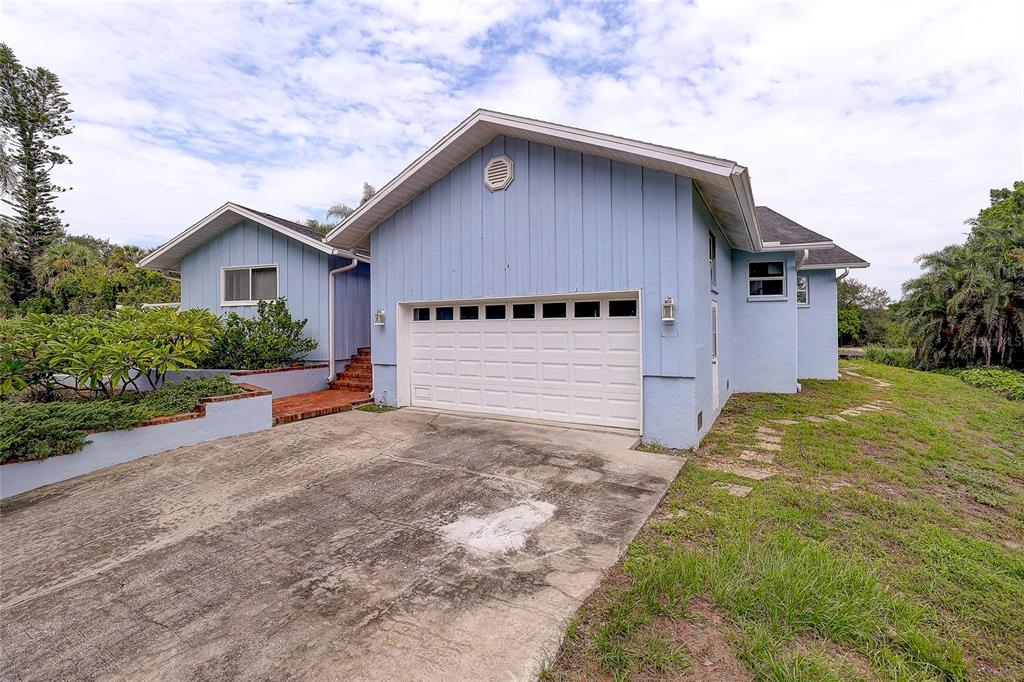 An aerial view shows a light blue house with a deck overlooking a calm lake — 3214 N SECLUSION DRIVE, SARASOTA, FL