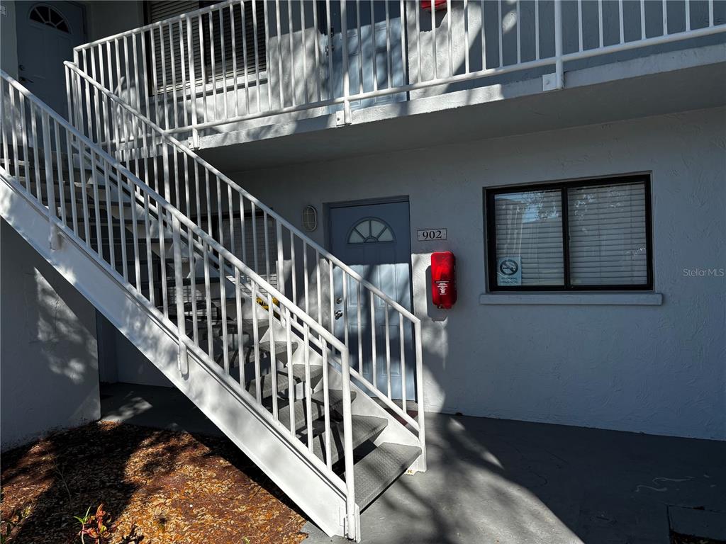 An exterior view of a ground-level apartment entrance with a staircase leading to the second floor — 5310 26TH STREET W UNIT 902, BRADENTON, FL