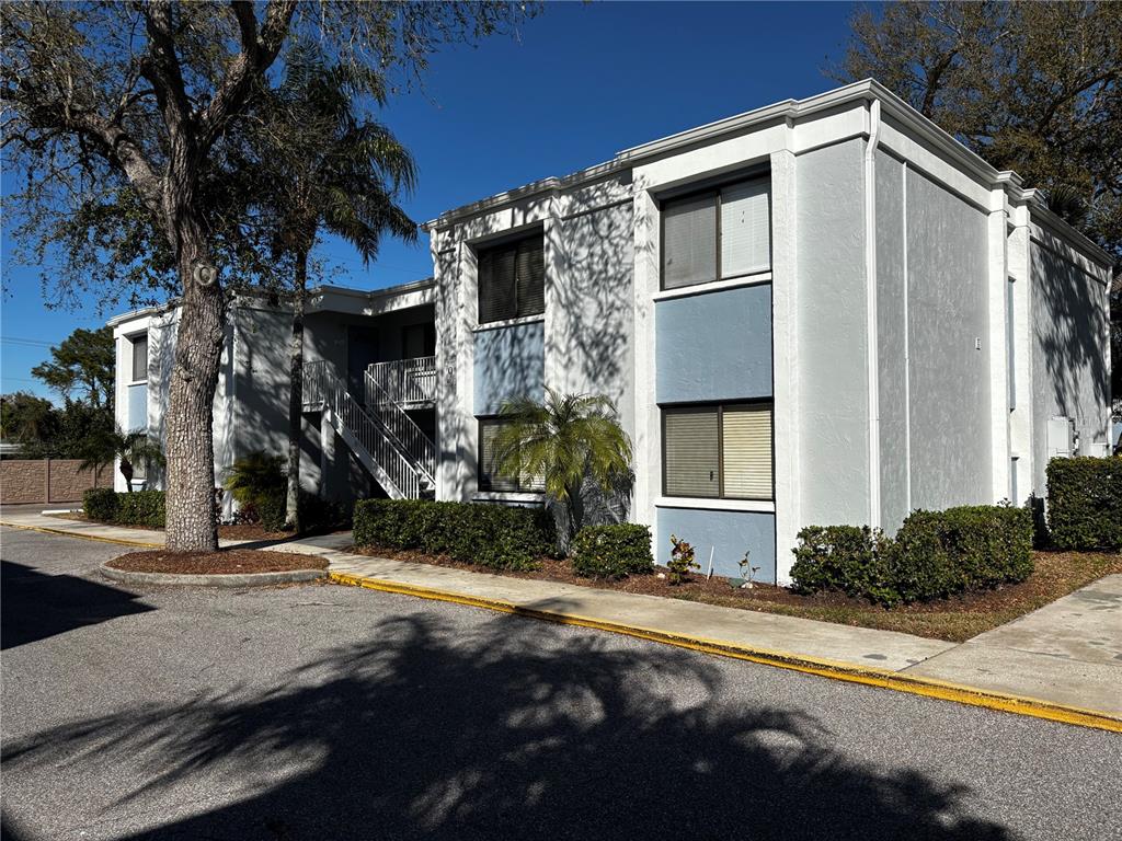 A two-story apartment building features white stucco walls, blue accents, and an exterior staircase — 5310 26TH STREET W UNIT 902, BRADENTON, FL