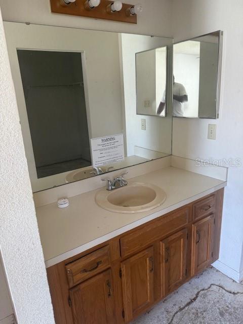 A bathroom vanity features a light-colored countertop, a single sink, and wooden cabinets — 3620 SAWGRASS DRIVE, TITUSVILLE, FL