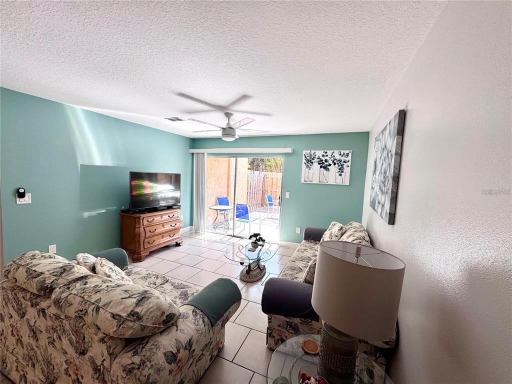 A living room features floral sofas, a television on a wooden dresser, and sliding doors — 3473 CLARK ROAD UNIT 171, SARASOTA, FL