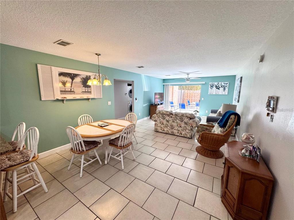 An open-concept living and dining area features tile flooring, light green walls, and sliding doors — 3473 CLARK ROAD UNIT 171, SARASOTA, FL