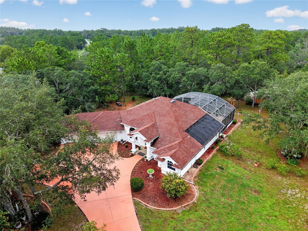 An aerial view of a house with a red roof, pool enclosure, and circular driveway — 2155 W FIR PLACE, BEVERLY HILLS, FL