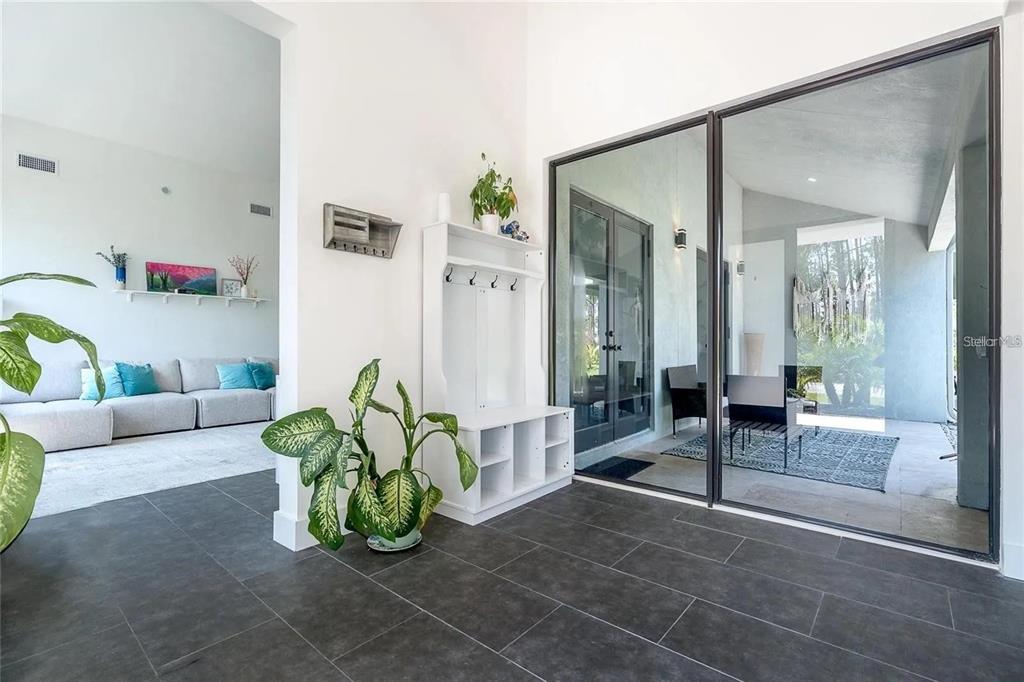 A bright entryway features dark tile flooring, a white hall tree, and large sliding glass doors — 8167 DITTMAR STREET, PORT CHARLOTTE, FL