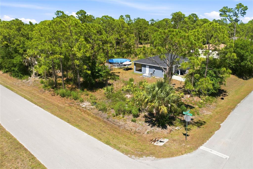 An aerial view shows a house with a backyard pool surrounded by dense pine trees — 27396 CORINTHIAN, DR, PUNTA GORDA, FL