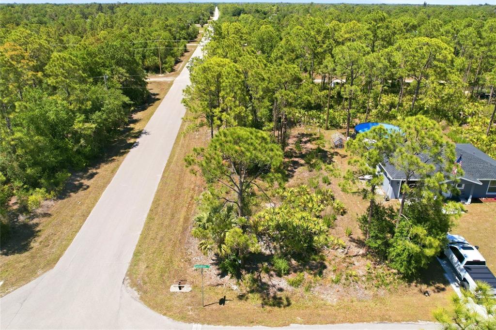 An aerial view shows a vacant, wooded lot next to a house with a pool — 27396 CORINTHIAN, DR, PUNTA GORDA, FL