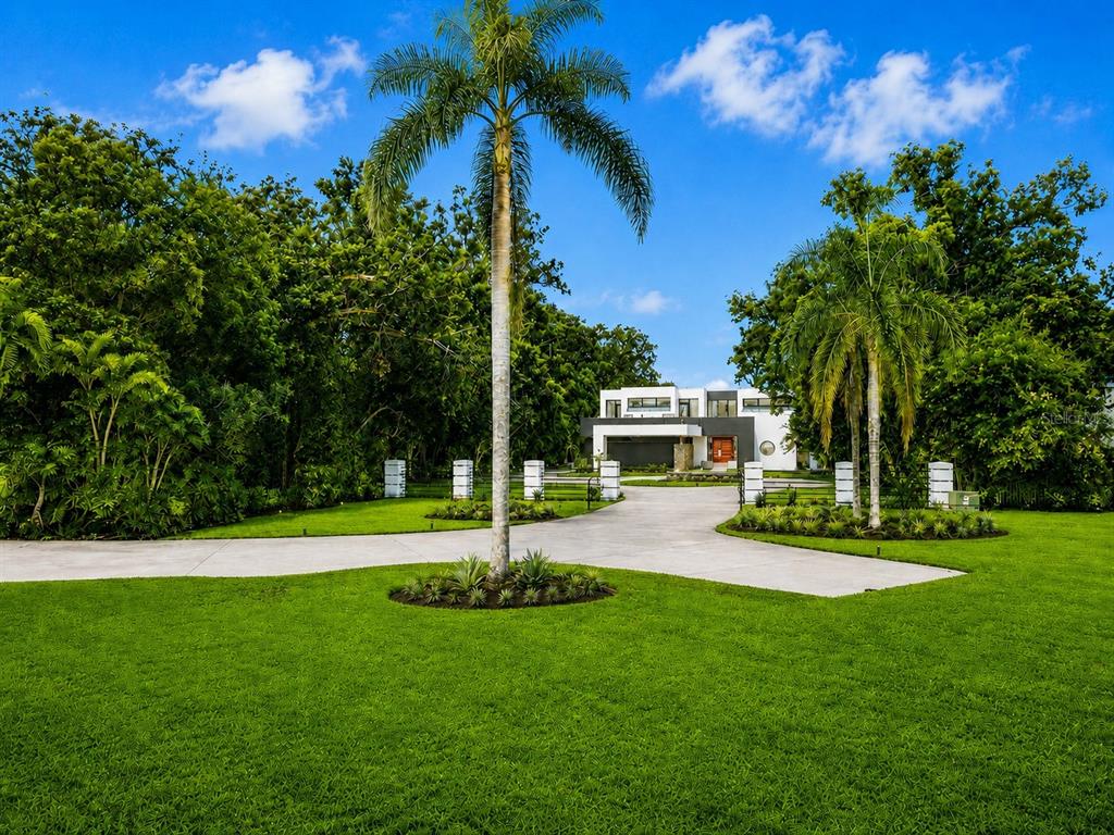 A covered outdoor balcony with wicker furniture, a ceiling fan, and a sunset water view — 3330 EHRLICH ROAD, TAMPA, FL