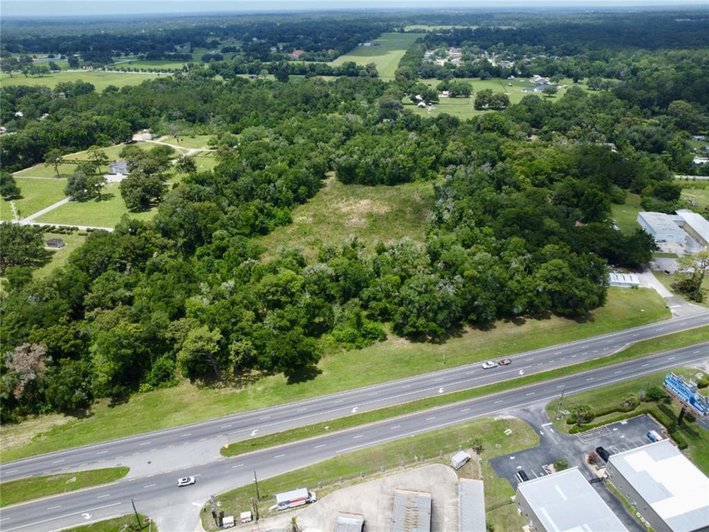 An aerial view shows a wooded lot situated next to a multi-lane highway — TBD S PINE AVENUE, OCALA, FL
