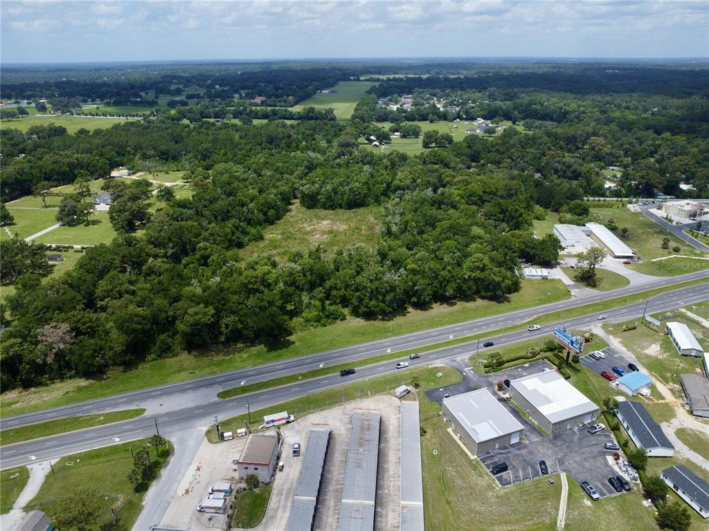 An aerial view shows a wooded lot situated between a highway and residential properties — TBD S PINE AVENUE, OCALA, FL