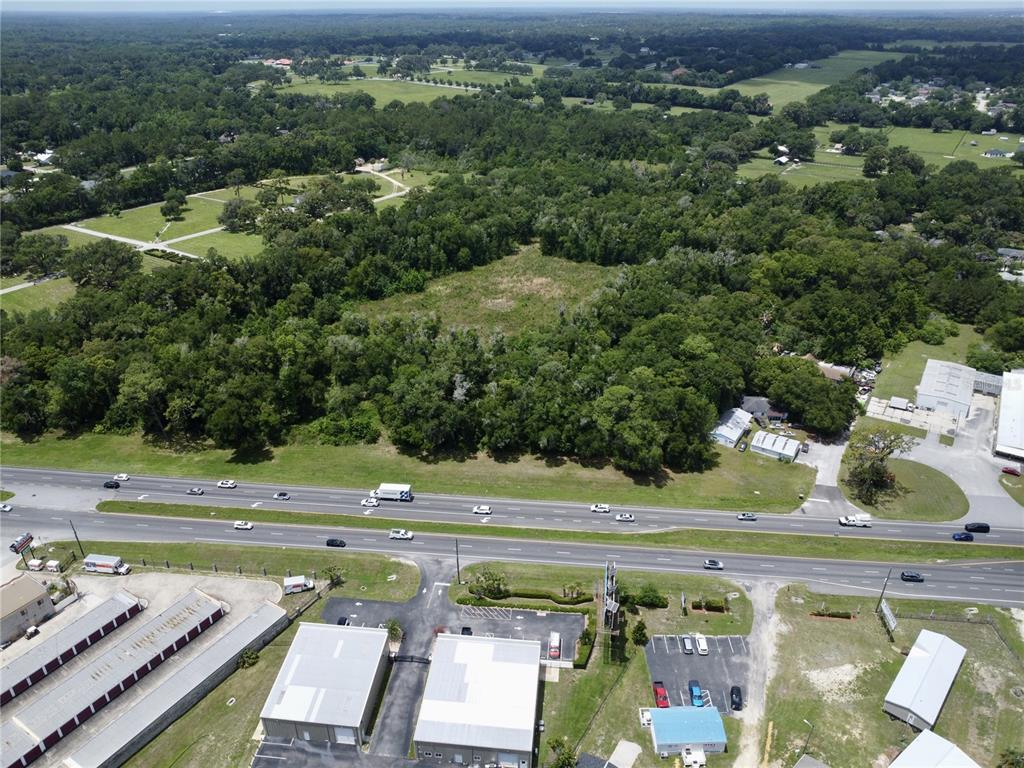 An aerial view shows a large, wooded lot situated behind a multi-lane highway — TBD S PINE AVENUE, OCALA, FL