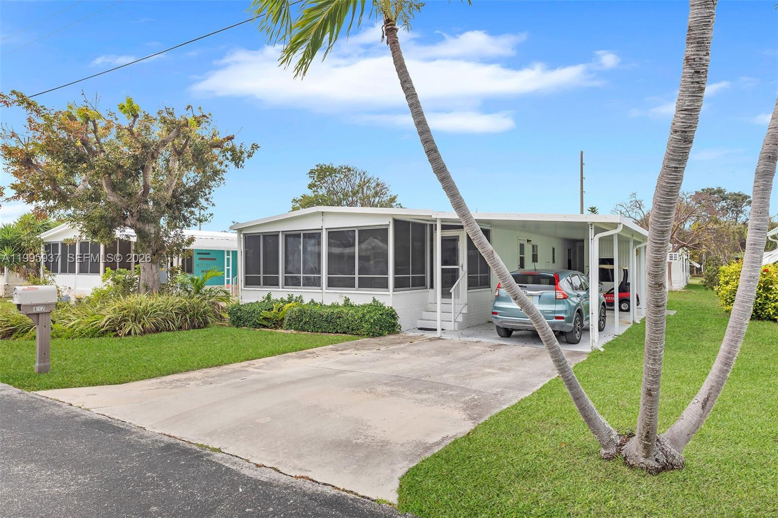 A single-story manufactured home features a screened-in porch, a carport, and a concrete driveway — 812 S Silver Cir, Key Largo FL 33037, KEY LARGO, FL