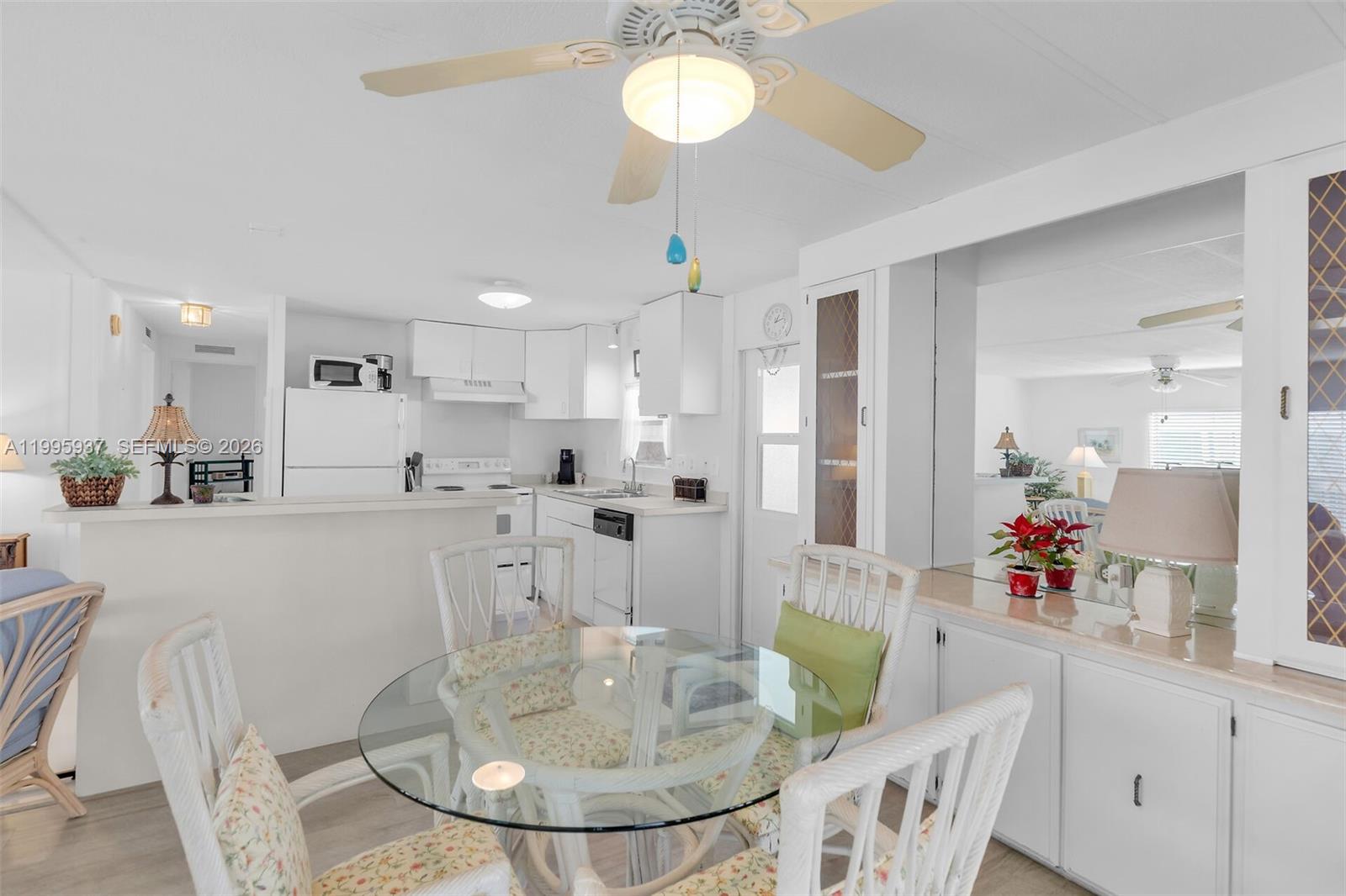 A dining area with a glass table and white wicker chairs sits before a kitchen — 812 S Silver Cir, Key Largo FL 33037, KEY LARGO, FL