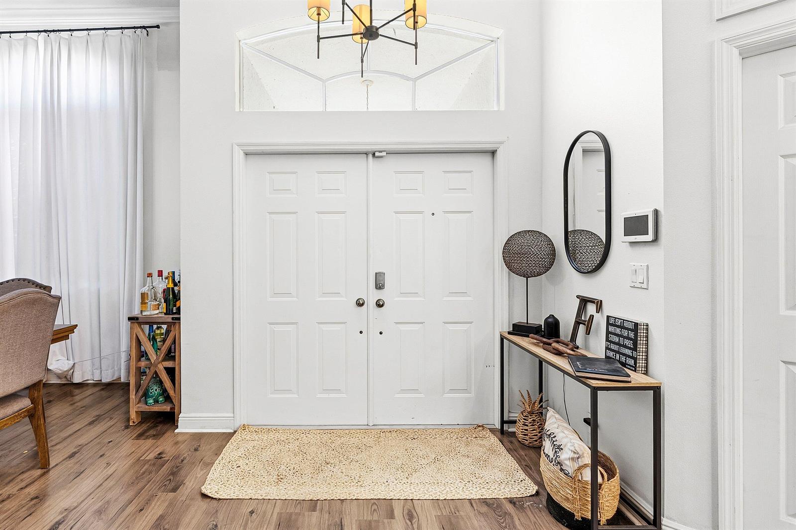 A bright entryway features double white doors, a console table, a mirror, and wood flooring — 17225 80th Street N, FL 33470, FL