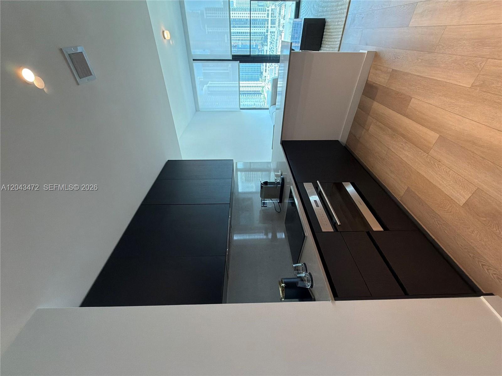 A modern kitchen features dark cabinetry, stainless steel appliances, and light wood flooring — 20 NE 11th St # 2409, Miami FL 33132, MIAMI, FL