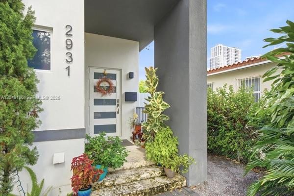A modern house entrance features a white exterior, a grey door, and potted plants — 2931 SW 38th Ct # 2, Miami FL 33134, MIAMI, FL