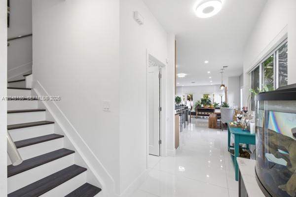 A staircase with dark treads leads to an open-concept living area with white tile floors — 2931 SW 38th Ct # 2, Miami FL 33134, MIAMI, FL