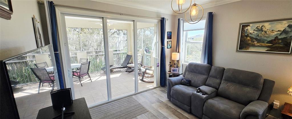 A living room features a gray reclining sofa, sliding glass doors, and a screened balcony — 45 RIVERVIEW BEND S UNIT 1937, PALM COAST, FL