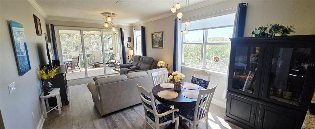 This open-concept living and dining area features wood-look flooring, a sliding glass door, and furniture — 45 RIVERVIEW BEND S UNIT 1937, PALM COAST, FL