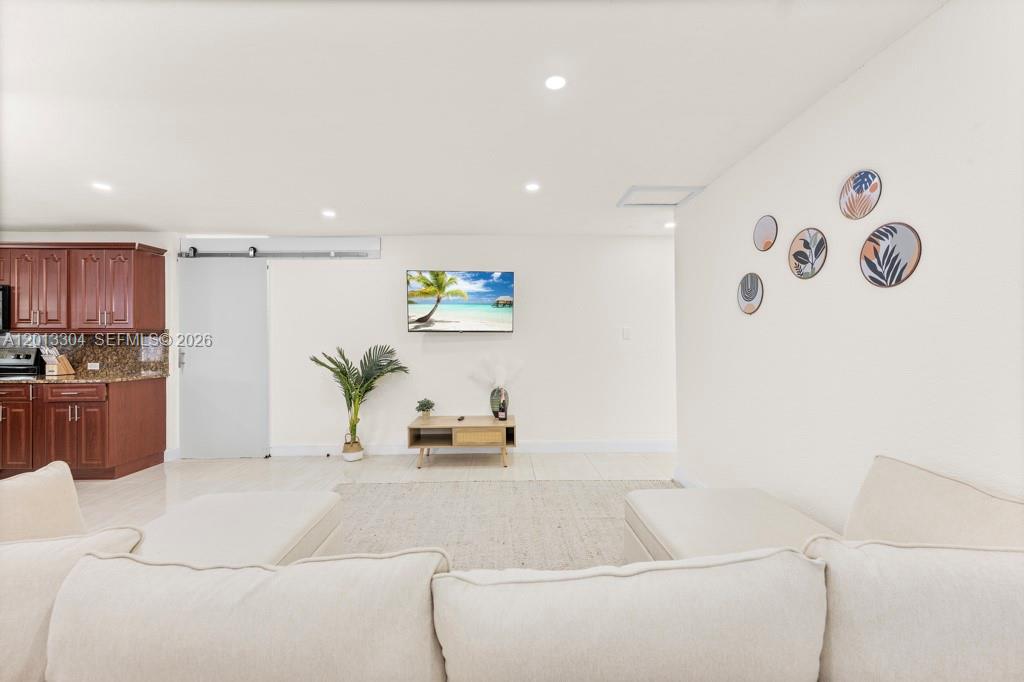 A living room features a white sectional sofa, a television, and a wooden media console — 2128 Dock St # 0, West Palm Beach FL 33401, WEST PALM BEACH, FL
