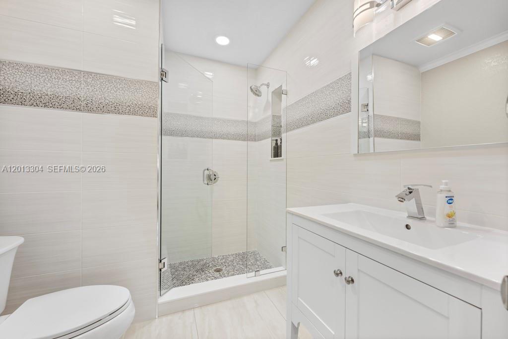 A modern bathroom features a white vanity, a glass-enclosed shower, and light-colored tiled walls — 2128 Dock St # 0, West Palm Beach FL 33401, WEST PALM BEACH, FL