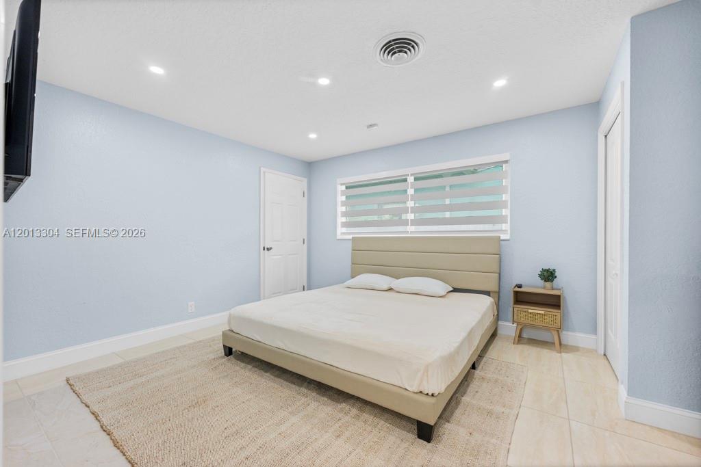 A bedroom features light blue walls, a beige upholstered bed, and a small wooden nightstand — 2128 Dock St # 0, West Palm Beach FL 33401, WEST PALM BEACH, FL