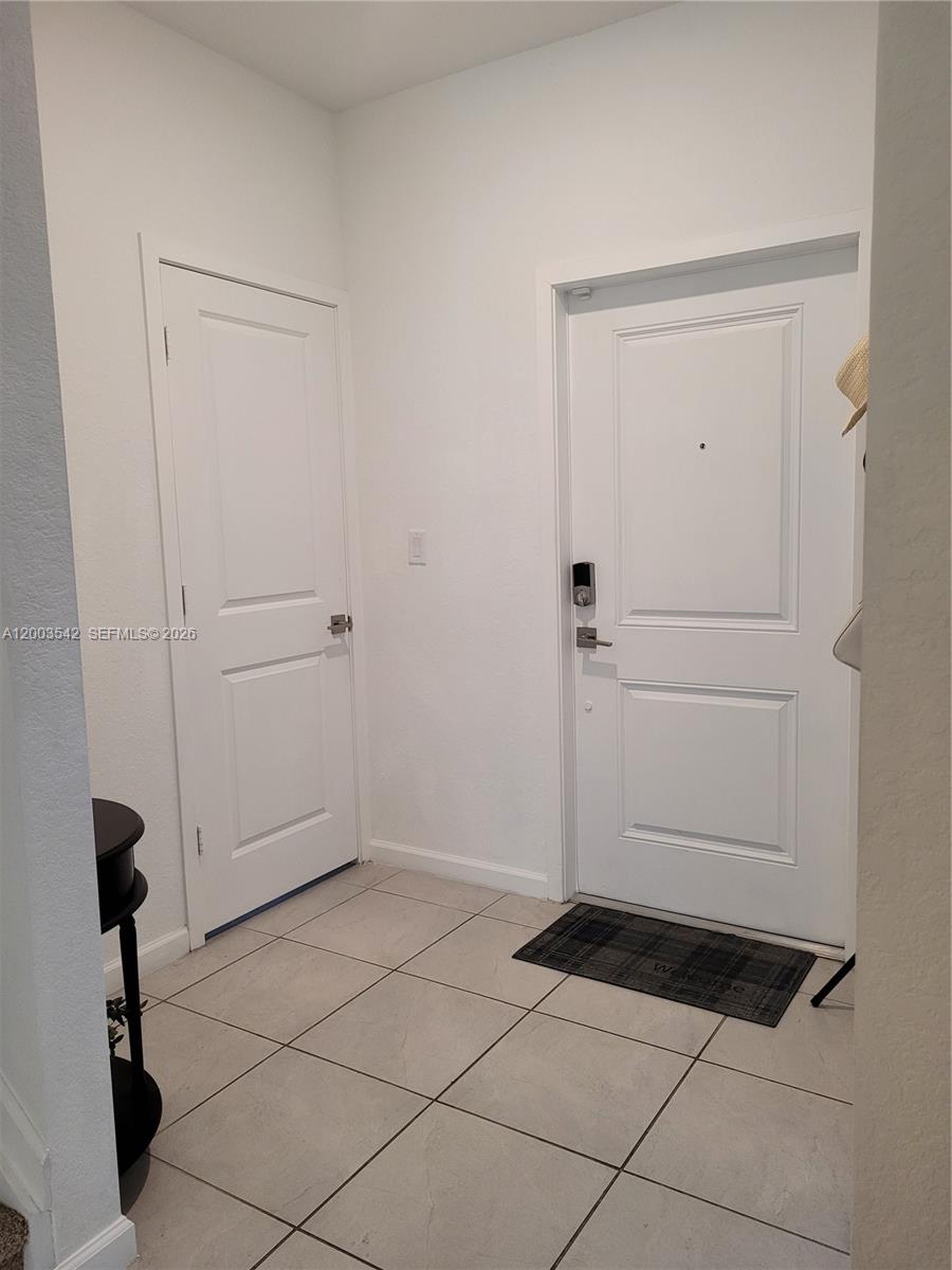 An entryway features white walls, tiled flooring, and two white paneled doors — 1015 SE 24th Ter, Homestead FL 33035, HOMESTEAD, FL