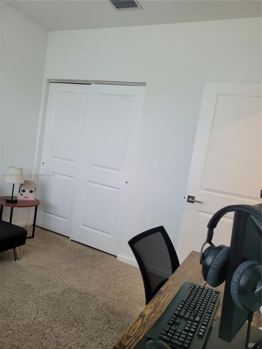 A room with carpeted flooring, a desk with computer equipment, a closet, and a door — 1015 SE 24th Ter, Homestead FL 33035, HOMESTEAD, FL