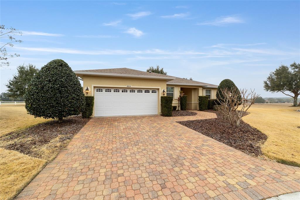 A single-story house with a paved driveway, a two-car garage, and landscaped front yard — 8835 SW 83RD COURT ROAD, OCALA, FL