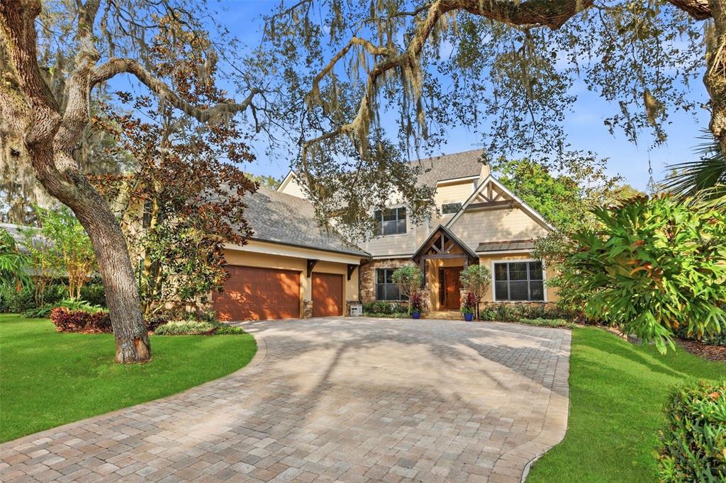 A two-story house with a paved driveway, a three-car garage, and large oak trees — 713 MAIN STREET, WINDERMERE, FL