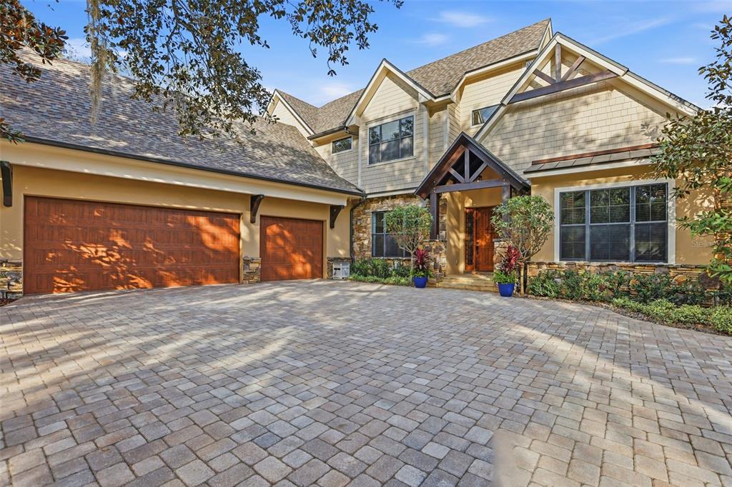 A two-story house with a stone facade, shingle roof, and a large paved driveway — 713 MAIN STREET, WINDERMERE, FL
