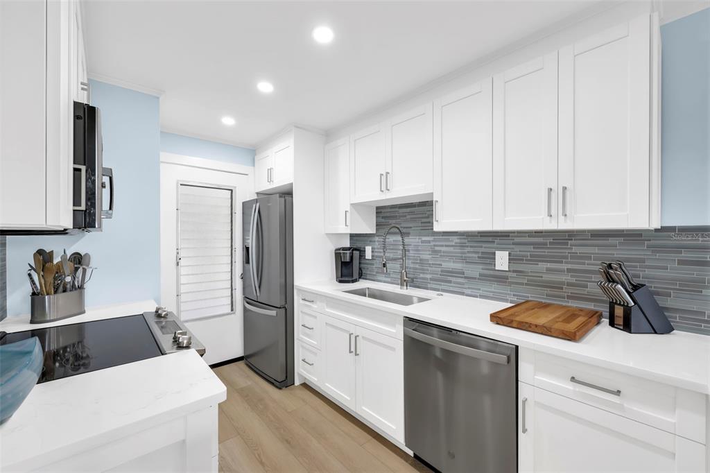 A kitchen with white cabinets, stainless steel appliances, and a gray tiled backsplash — 1300 GULF SHORE BOULEVARD N UNIT 700, NAPLES, FL