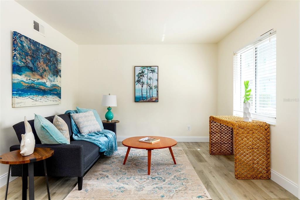 A living room features a dark sofa, a round coffee table, and a woven console table — 1142 SUNSET POINT ROAD, CLEARWATER, FL