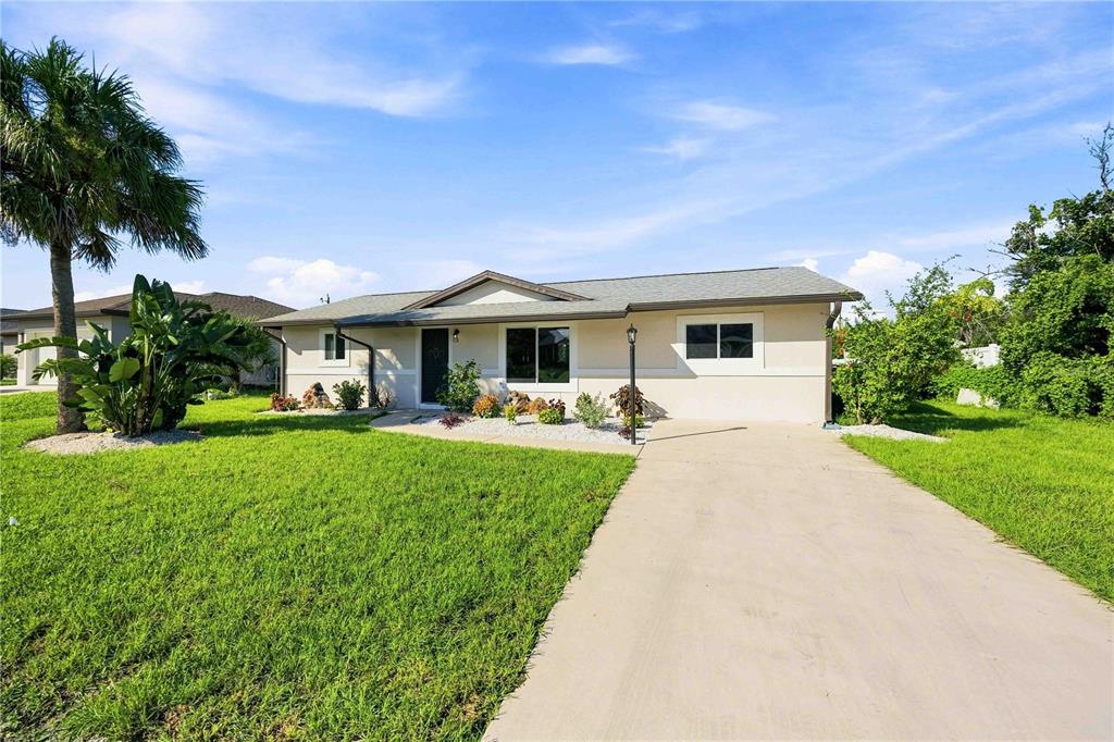 A single-story house with a concrete driveway, a palm tree, and a green lawn — 7321 BOLTEN LANE, PORT CHARLOTTE, FL