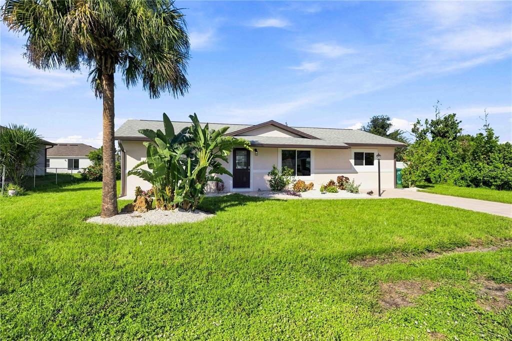 A single-story house with a palm tree, landscaping, and a driveway under a blue sky — 7321 BOLTEN LANE, PORT CHARLOTTE, FL