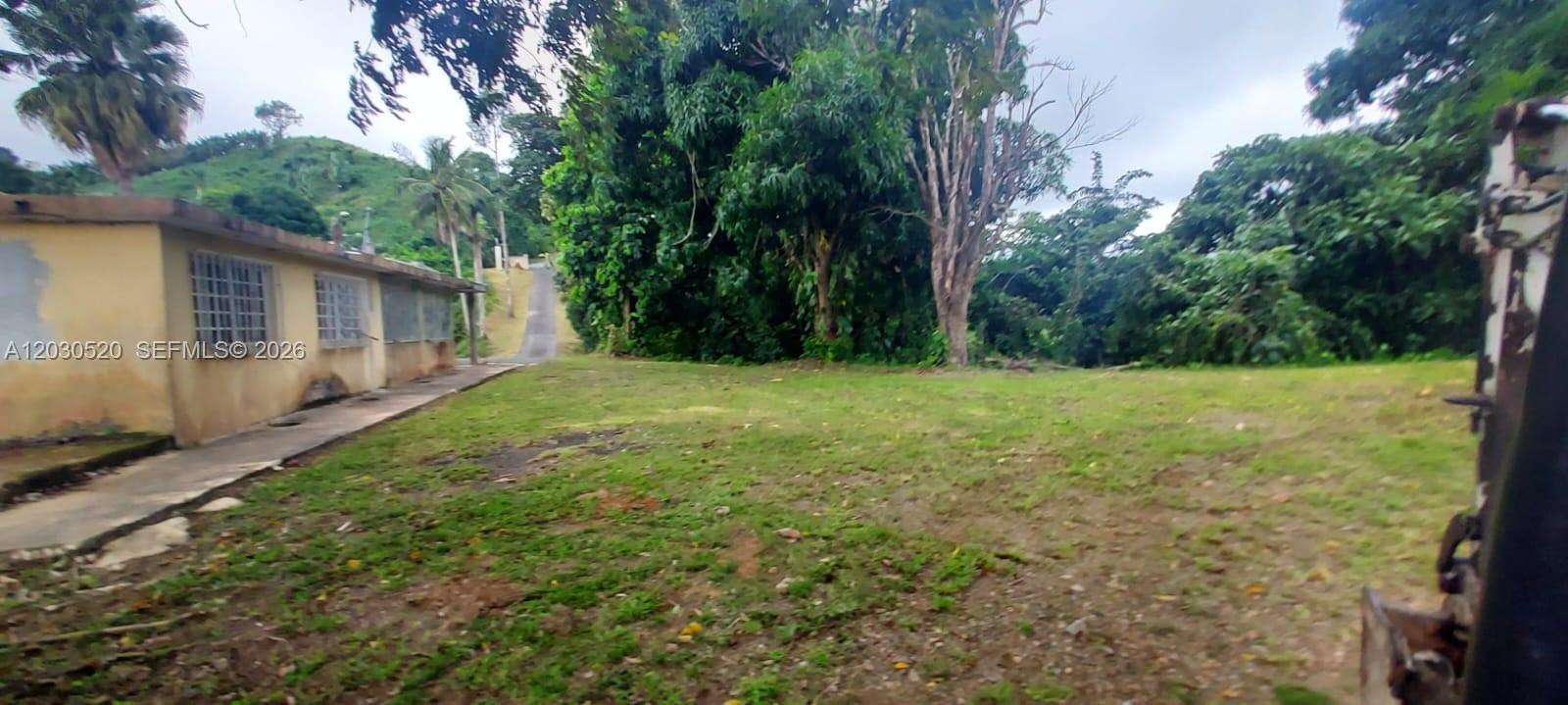 A view of a grassy yard next to a single-story building with barred windows — #22, Bo Vaga vaga, PR 00687, PR