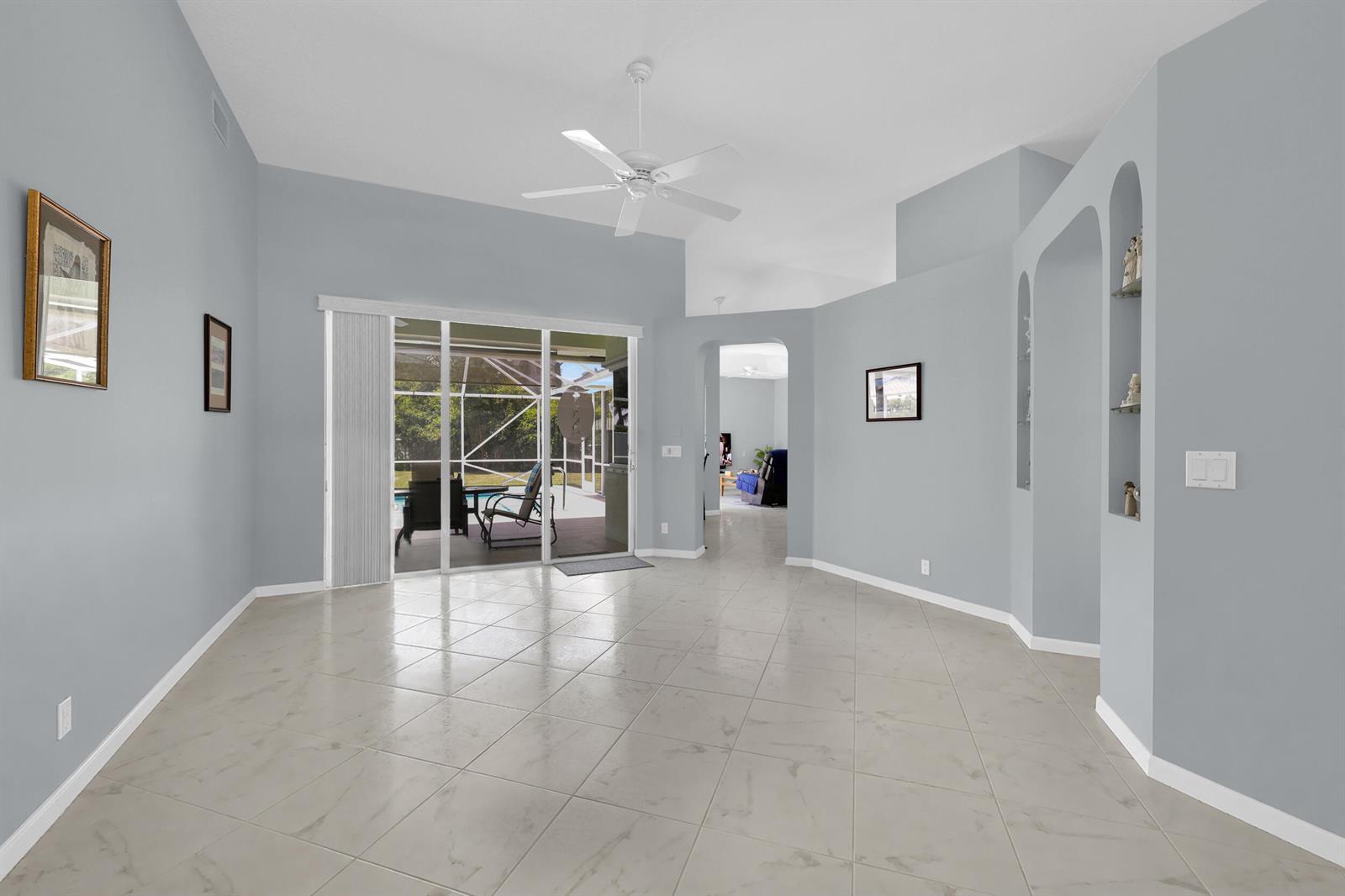 A bright, open-concept living area with light gray walls, tile flooring, and sliding glass doors — 521 Cypress Circle, Tequesta FL 33469, TEQUESTA, FL